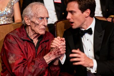 In a hall of polished medals and perfect tuxedos, one old man in a cheap red jacket refused to move.